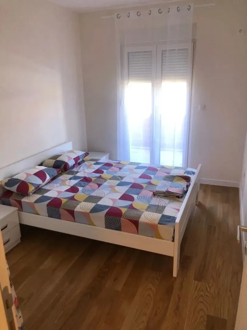 Svjetla spavaća soba sa bračnim krevetom i prozorom.