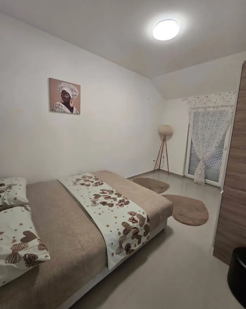 Uređena spavaća soba sa bračnim krevetom i detaljima u enterijeru.