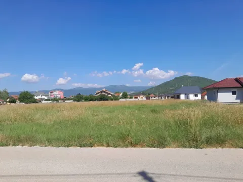 Pogled na ravno zemljište sa travom i okolne kuće u daljini. - image 2