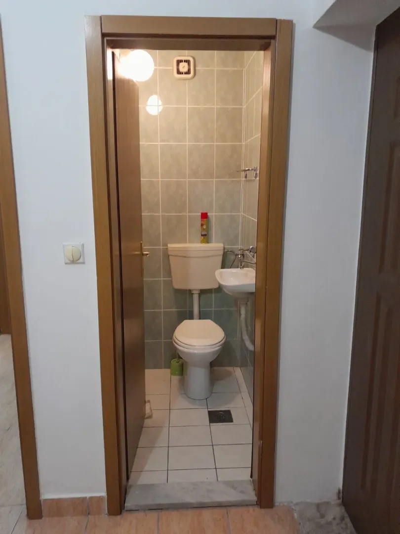 Mali toalet sa lavaboom i WC šoljom viđen kroz otvorena vrata.