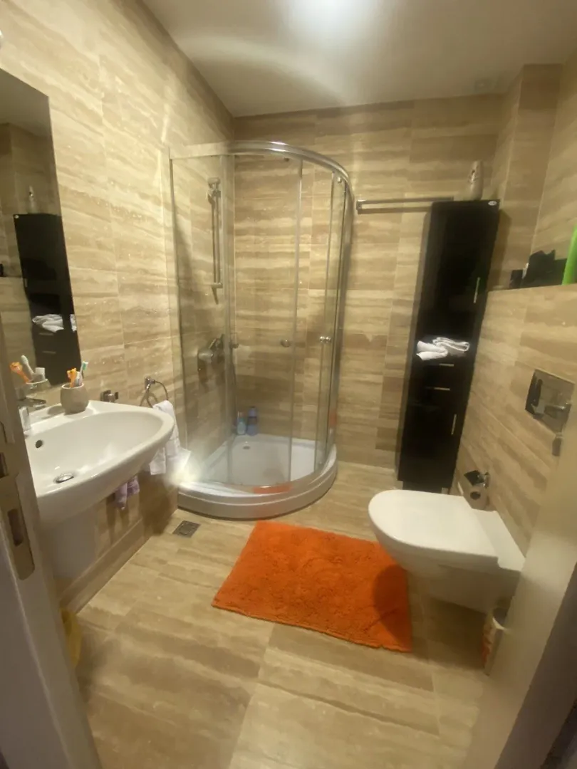 Kupatilo sa tuš kabinom, lavaboom i toaletom u bež tonovima.