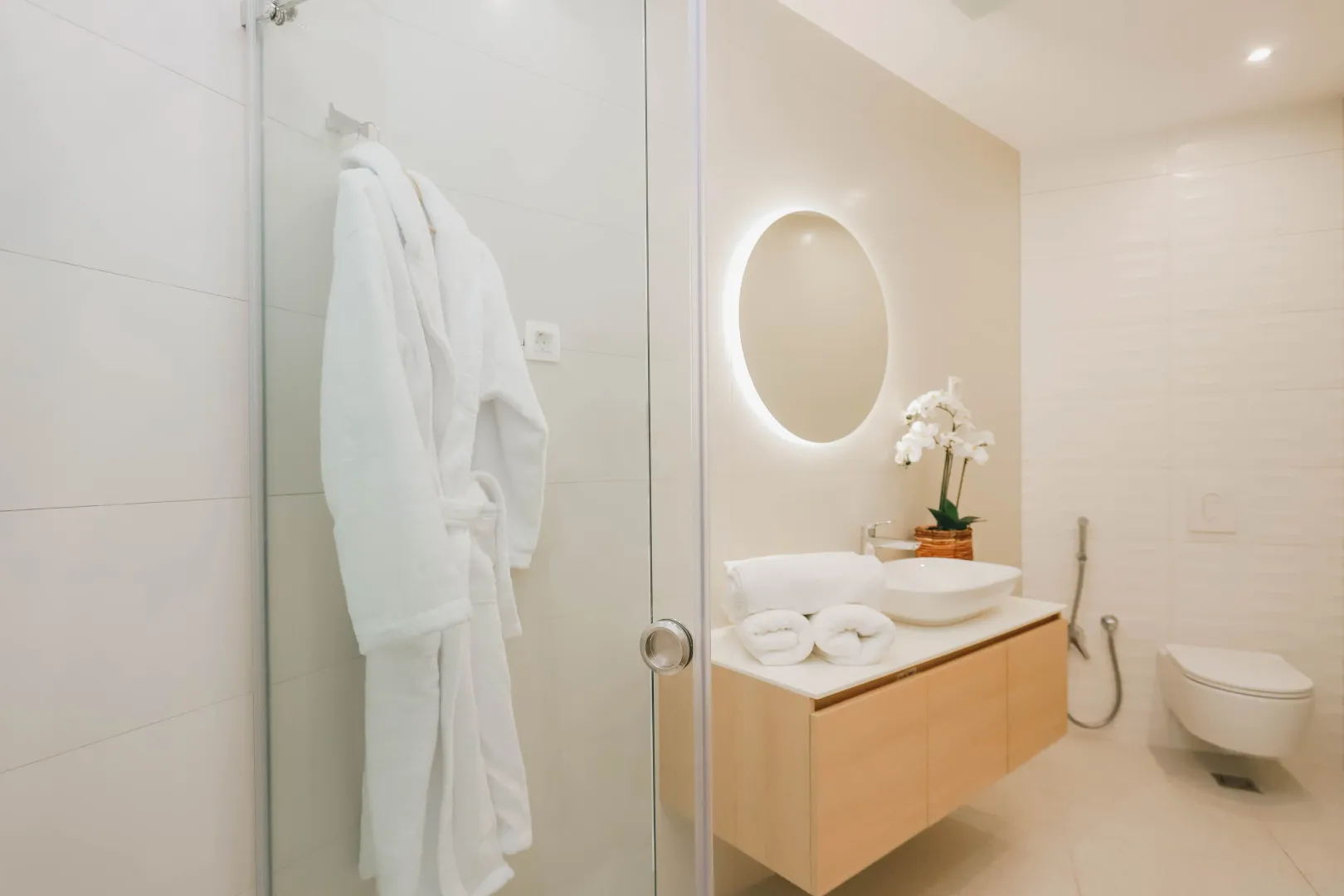 Modern bathroom with a washbasin, shower cabin, and wall-mounted toilet.