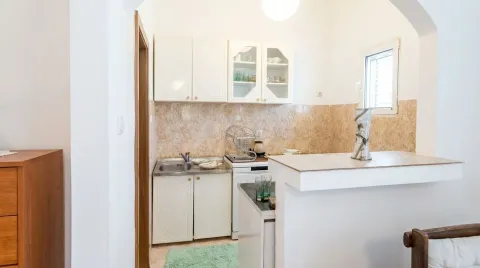 Smaller kitchen with white cabinets and a breakfast bar. - image 3