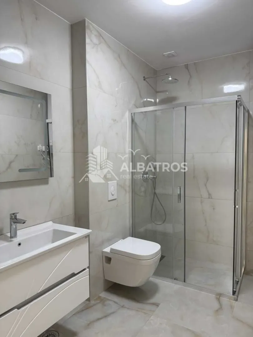 Moderno opremljeno kupatilo sa tuš kabinom, umivaonikom i WC šoljom.