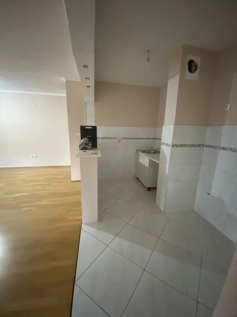 Prazan kuhinjski prostor sa pločicama i šankom u novom stanu.