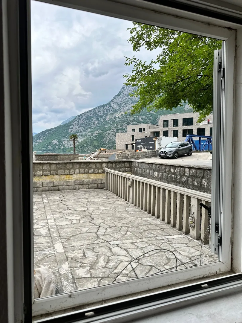 View through the window of the terrace, surrounding buildings, and mountains.