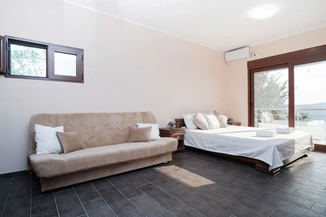Spacious bedroom with a bed, sofa, and access to the terrace.