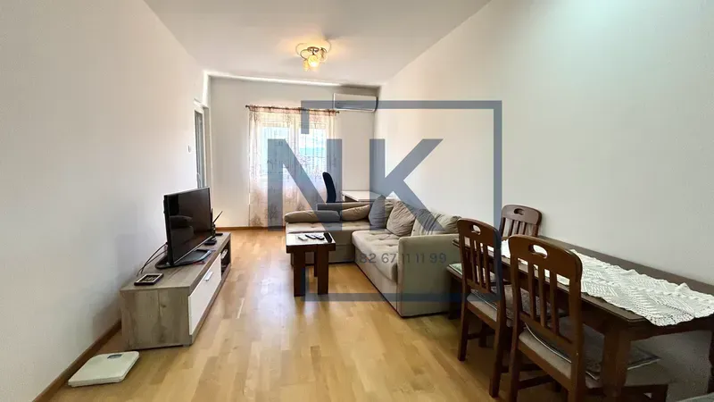 Dnevna soba sa garniturom, televizorom i trpezarijskim stolom.