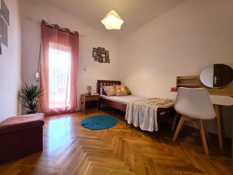 Furnished bedroom with a bed, desk, and balcony door. - image 12