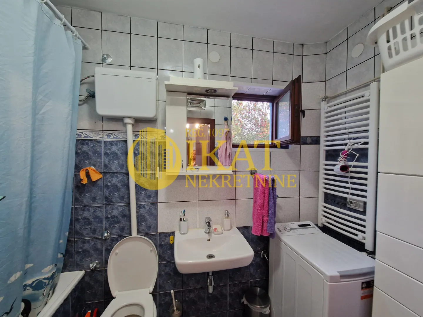 Manje kupatilo sa lavaboom, WC šoljom, mašinom za veš i prozorom.