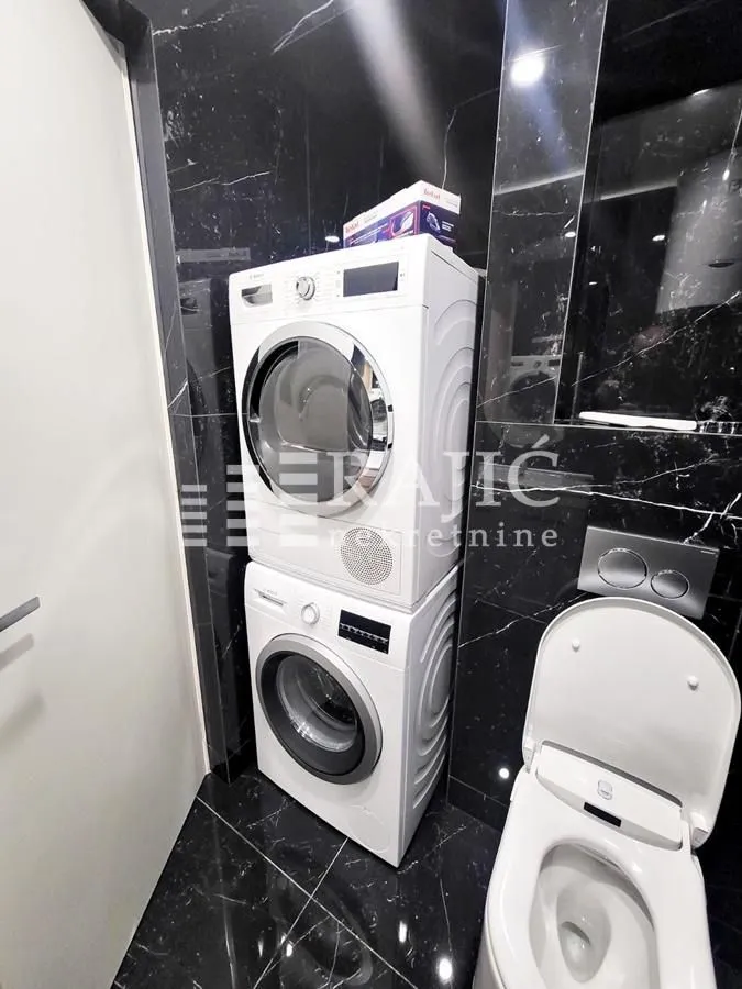 Modernly equipped bathroom with built-in washing and drying machine.