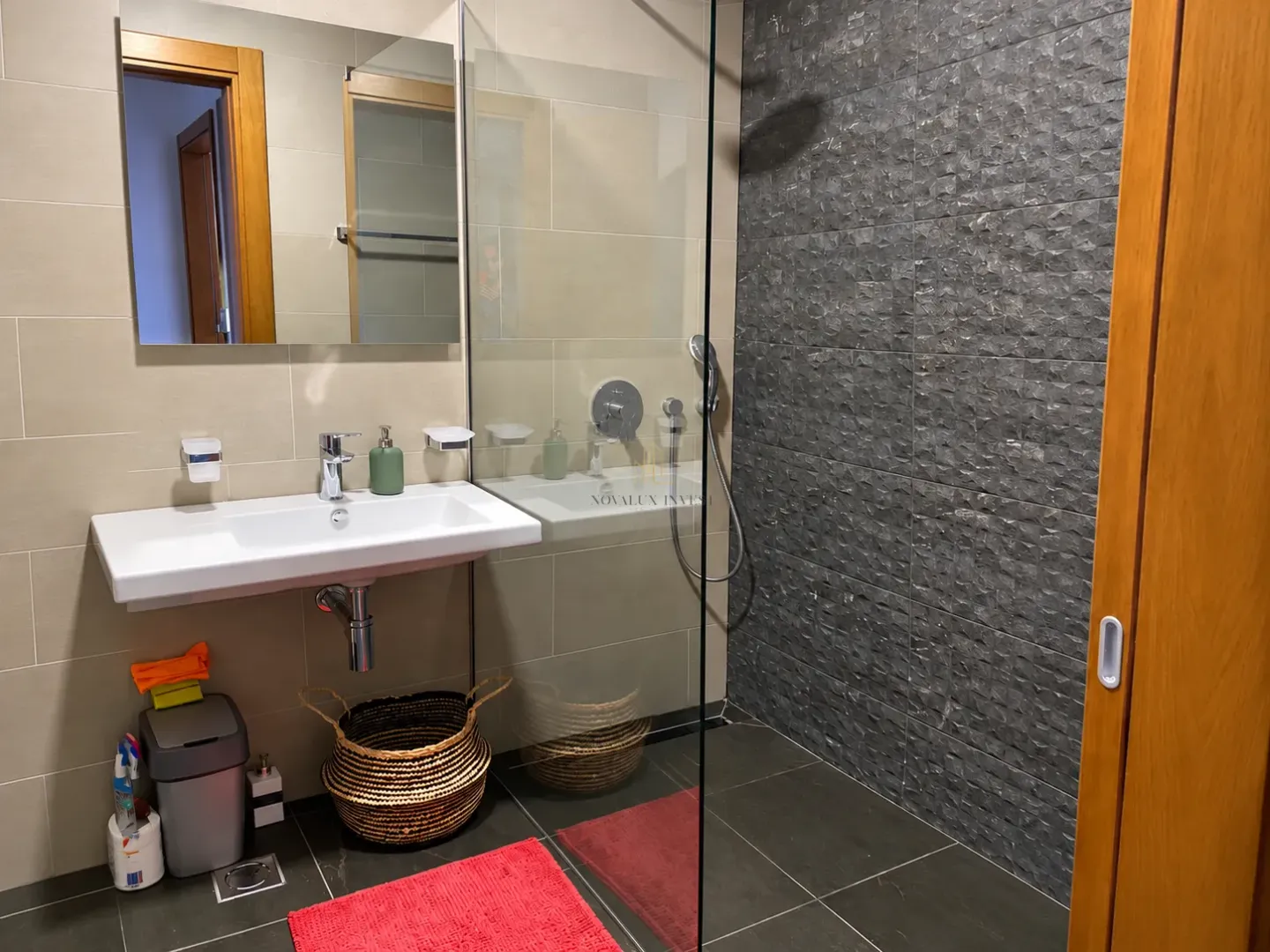 Moderne kupatilo sa umivaonikom i tuš kabinom sa staklenom pregradom.