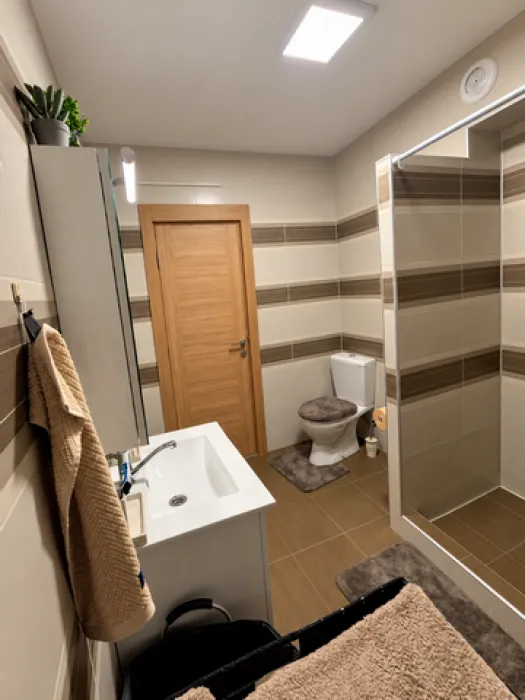 Savremeno opremljeno kupatilo sa tuš kabinom, umivaonikom i WC šoljom.