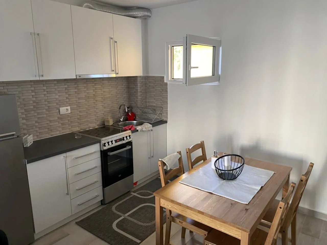 Small white kitchen with a dining table and chairs.