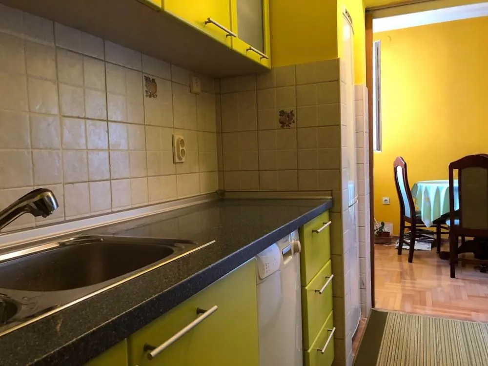 View of the kitchen with green cabinets and a sink, with a passage to the dining area.