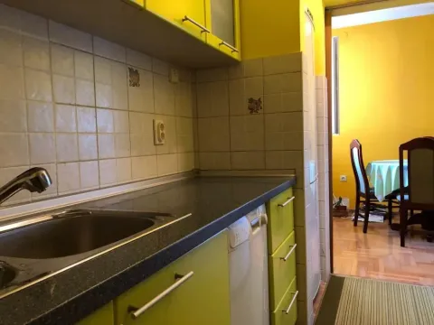 View of the kitchen with green cabinets and a sink, with a passage to the dining area. - image 9