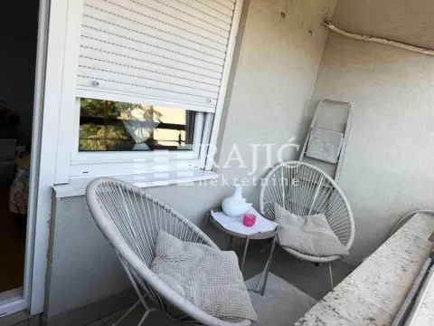 Small covered terrace with two chairs, a small table, and a window with blinds. - image 5