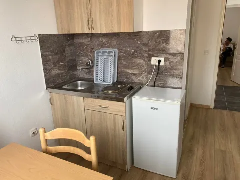 Small kitchen with a sink, stove, and refrigerator in the room. - image 2