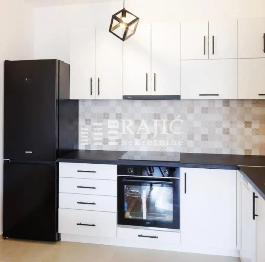 Modern white kitchen with a black refrigerator and built-in appliances.