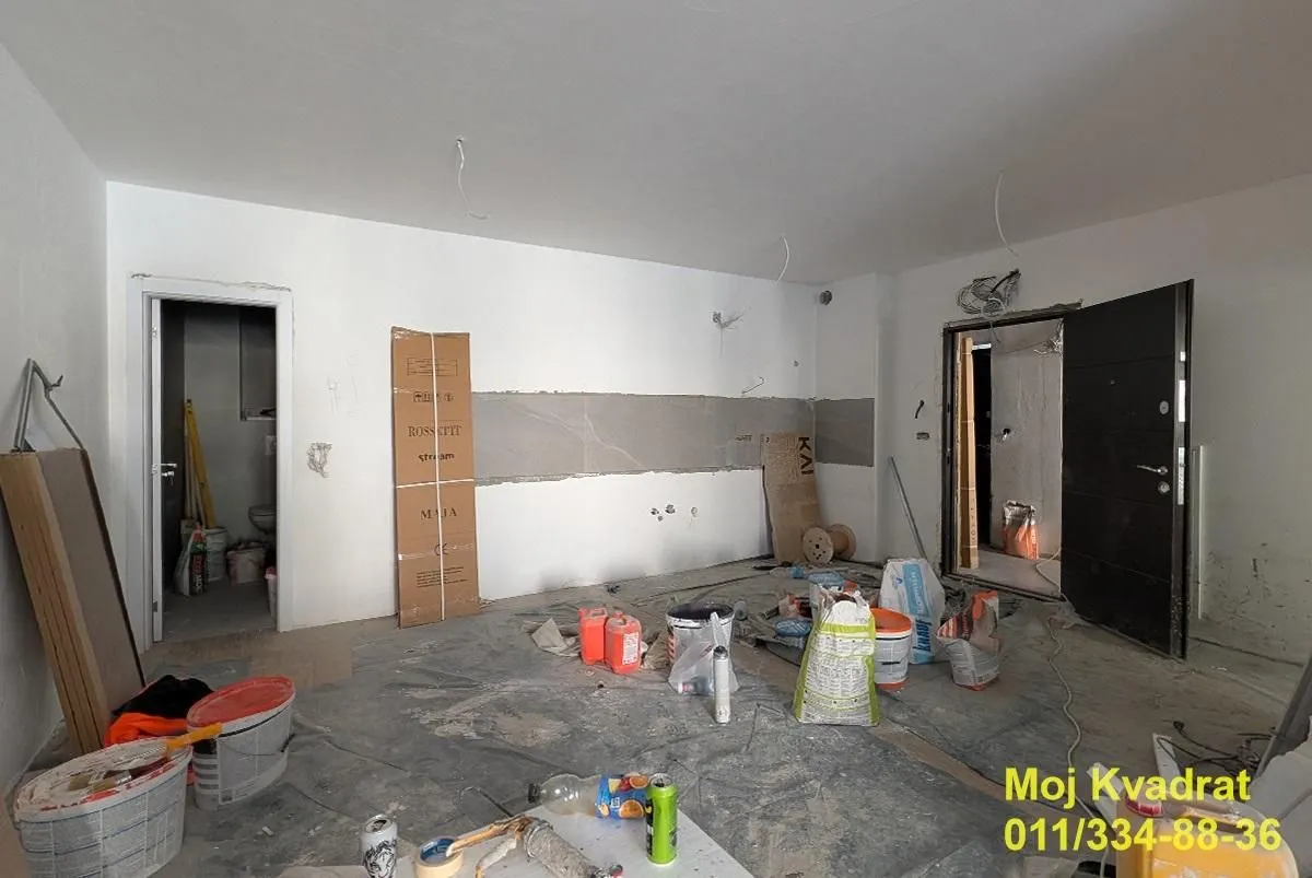 Prikaz prostorije u toku renoviranja sa građevinskim materijalom i alatima.