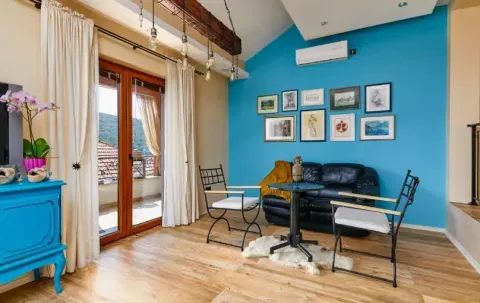 Living room with a blue accent wall, black leather sofa, small table, and balcony access. - image 7
