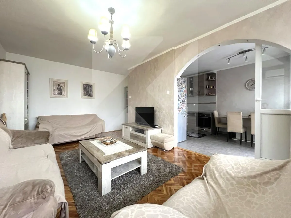 Living room with a sofa, coffee table, and TV, with a view of the dining area and kitchen.