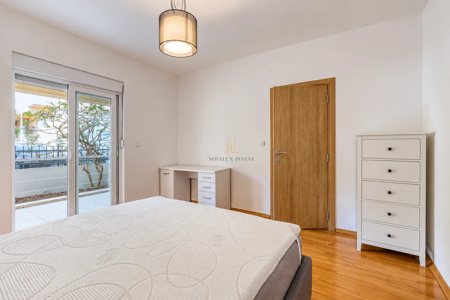 Bedroom with a bed, desk, dresser, and access to the terrace.