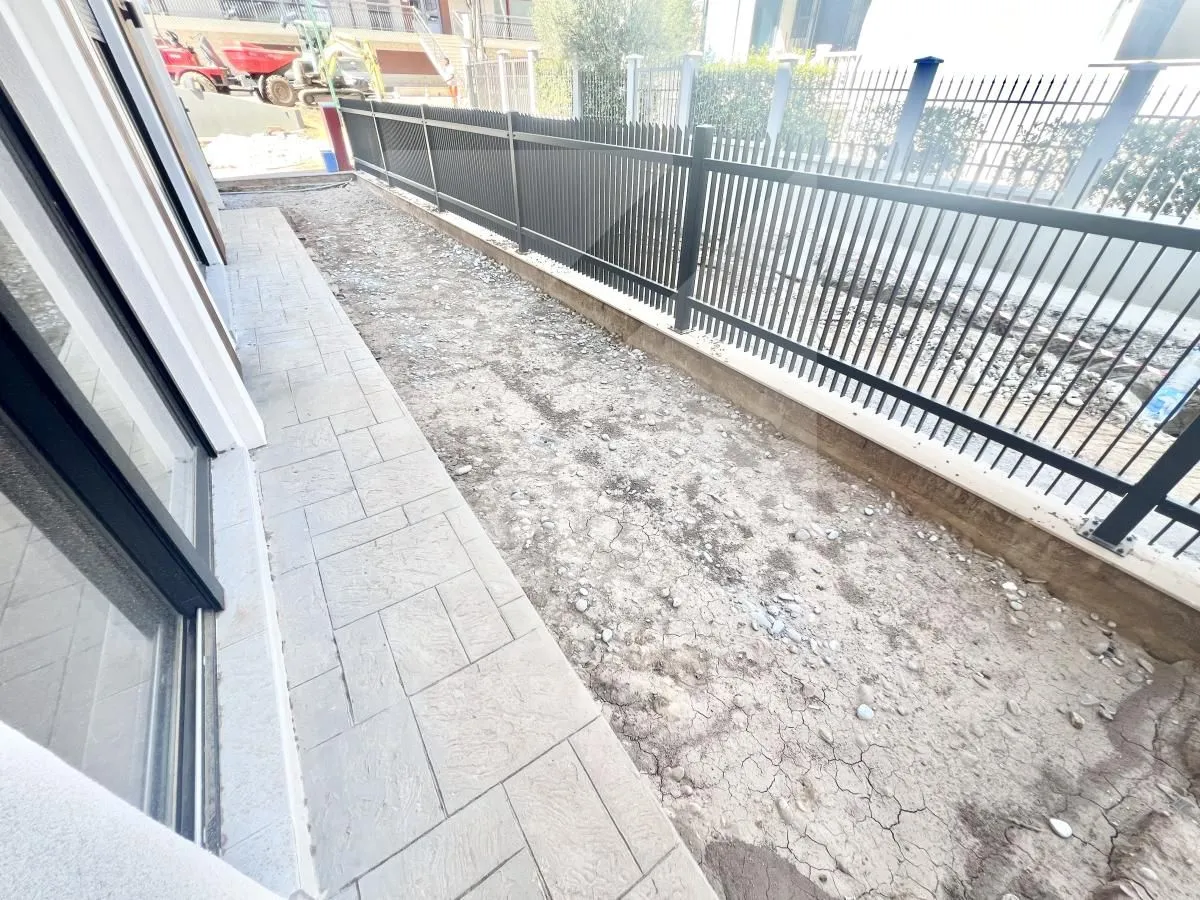View of the yard area and fence in front of the property under construction.