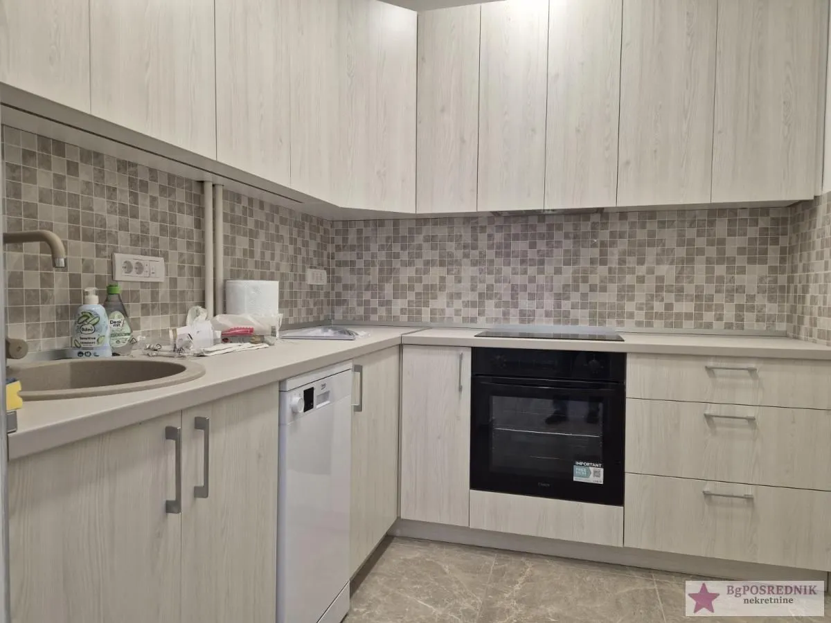 Kitchen equipped with light cabinets, built-in oven, hob, and sink.