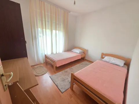 Bedroom with two wooden beds, a wardrobe, and a window with light curtains. - image 7