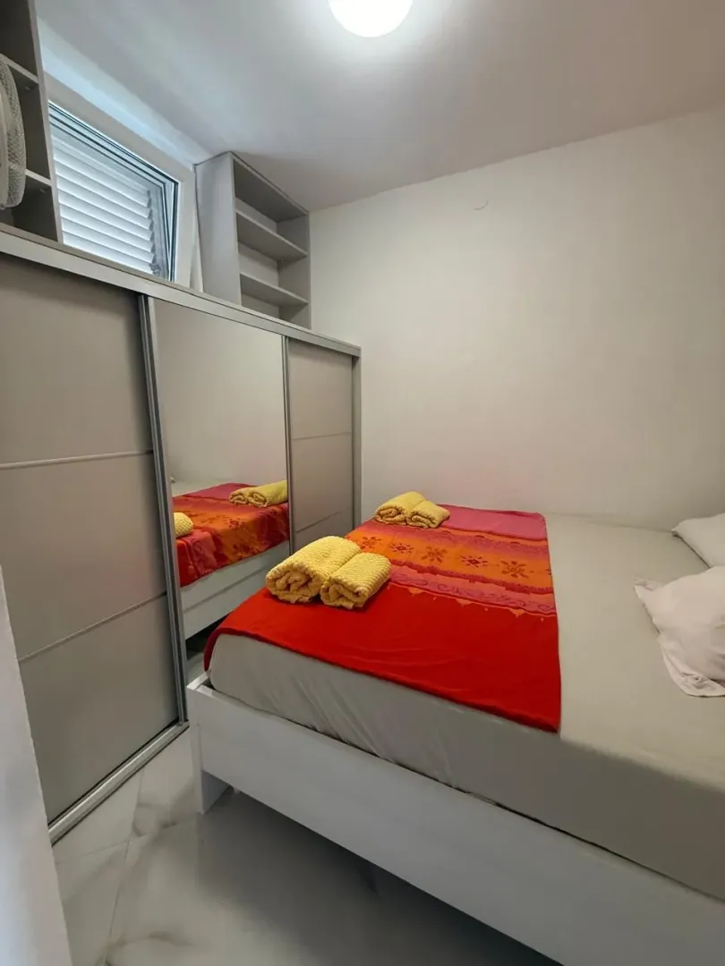 Spavaća soba sa bračnim krevetom i ugradnim plakarom sa ogledalom.