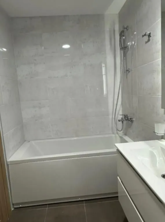 Small bathroom with a bathtub and white washbasin.