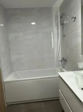 Small bathroom with a bathtub and white washbasin. - image 6