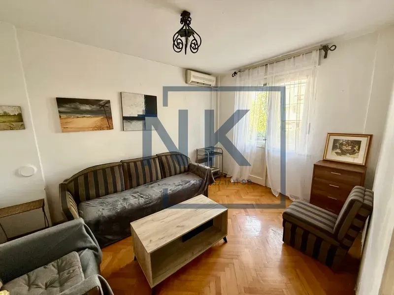 Living room with a sofa, coffee table, and parquet flooring.