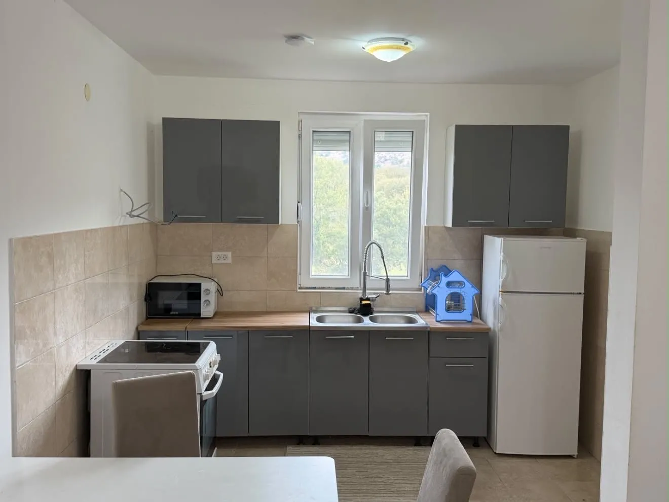 Small kitchen with grey cabinets and a white refrigerator.