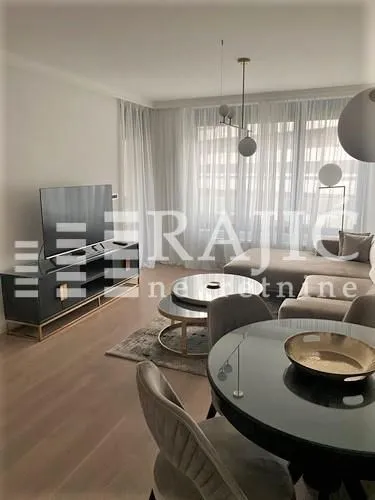 Modern living room with a sofa, TV unit, and dining table.