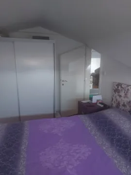 Spavaća soba u potkrovlju sa ljubičastom posteljinom i bijelim ormarom. - image 13