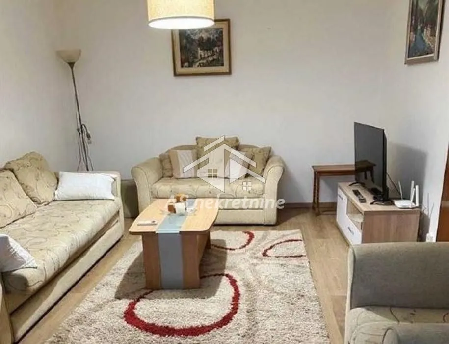 Furnished living room with sofa set, coffee table, and television.