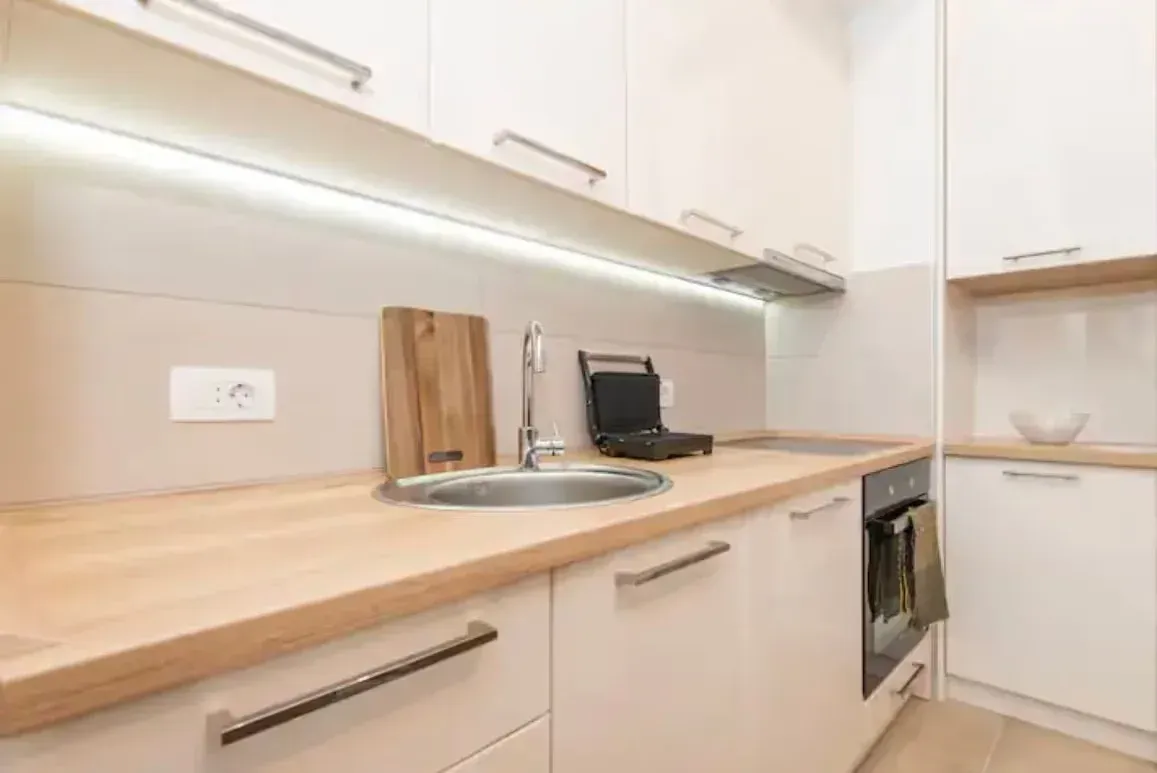 Modern kitchen with white units and a wooden countertop.