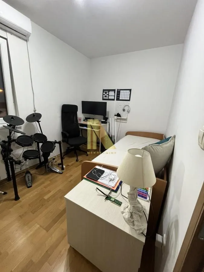 Manja spavaća soba sa krevetom, radnim stolom i elektronskim bubnjevima.