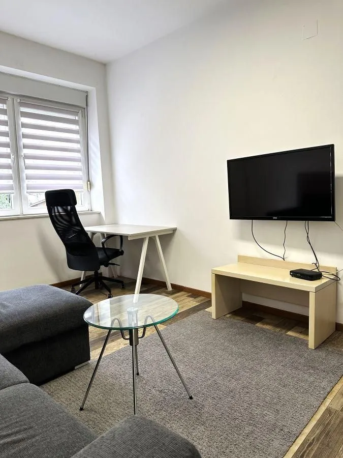 Living room furnished with a sofa, desk, and TV.