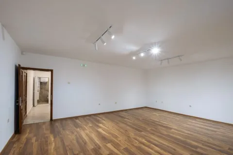 Empty room with white walls, wooden flooring, and ceiling lighting. - image 8