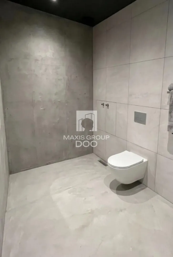 Moderno opremljeno kupatilo sa sivim pločicama i konzolnom wc šoljom.