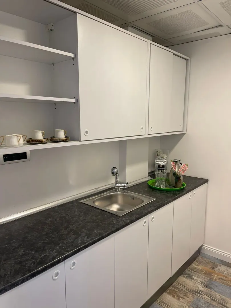 Small white kitchenette with a dark countertop and upper cabinets.