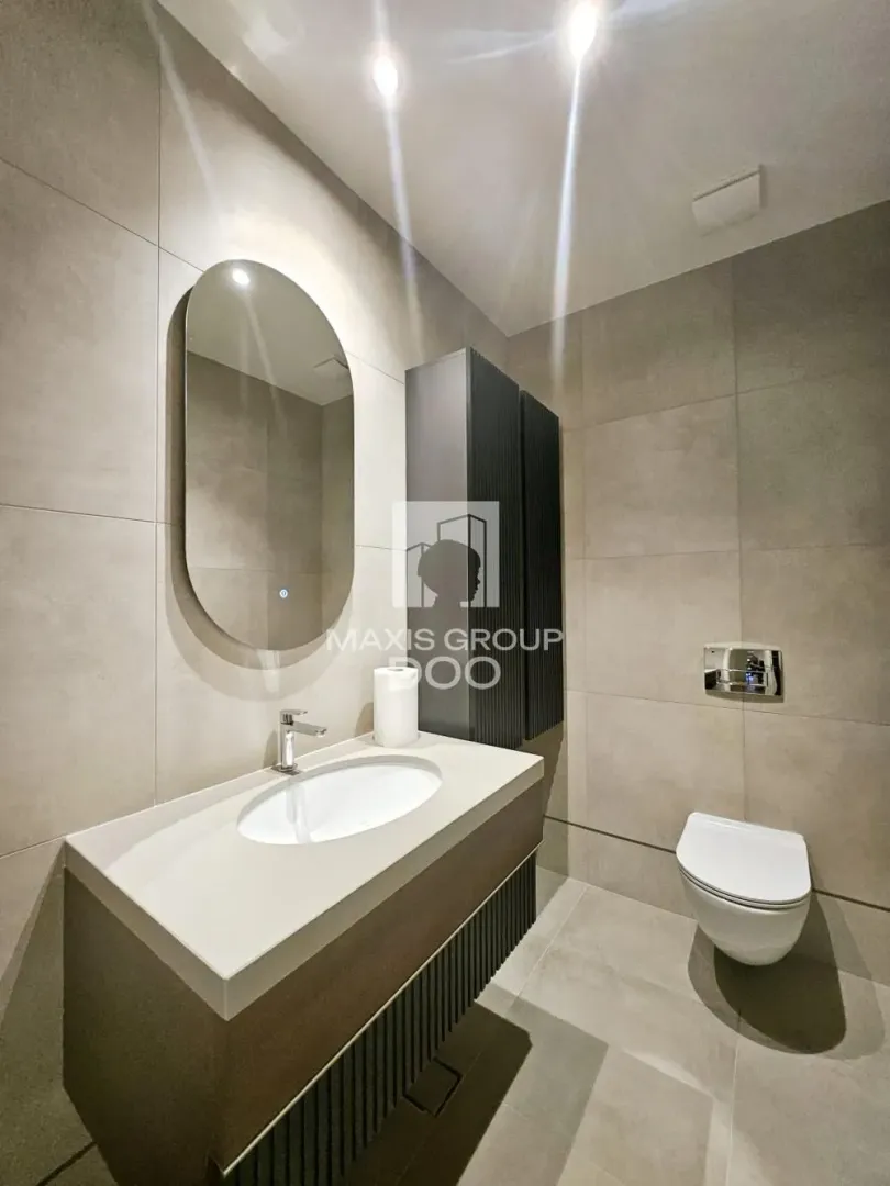 Modern bathroom with a sink, mirror, and toilet.