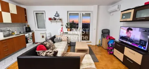 Dnevna soba sa garniturom, televizorom i kuhinjom u pozadini. - image 4