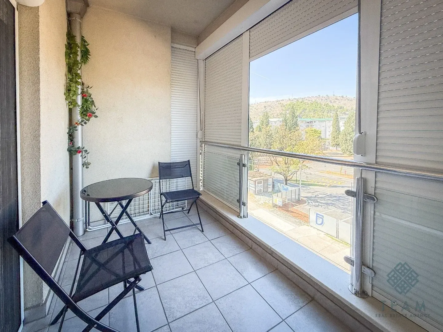 Covered balcony with a table, chairs, and a view of the surroundings.