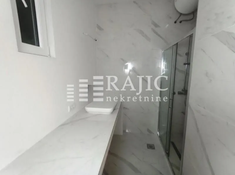 Modern bathroom with marble tiles and a walk-in shower.