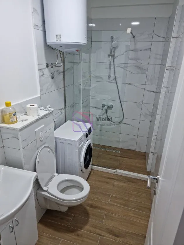 Kupatilo sa tuš kabinom, WC šoljom, umivaonikom i veš mašinom.