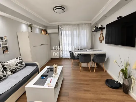 Dnevni boravak sa garniturom, trpezarijskim stolom i velikim televizorom na zidu. - image 2
